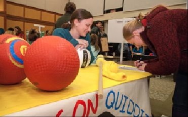 A member of the Quidditch Team, Dirigible Plums, signing up a new member at Activities Night.