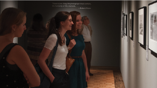 Students examine photos from the new exhibition by various artists featured by the Trout Gallery.