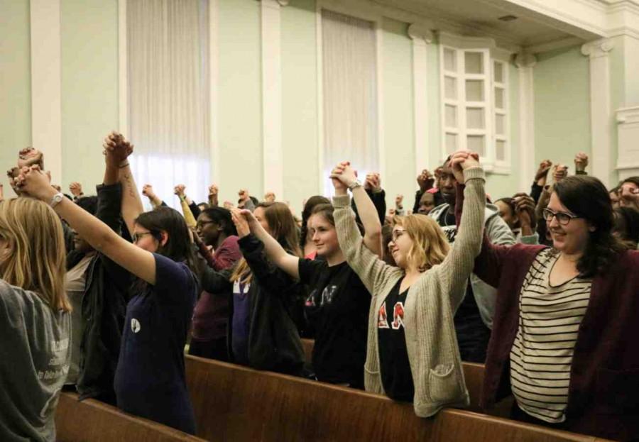 Students stand with their fists raised in solidarity with the victims of sexual assault in Allison Hall.